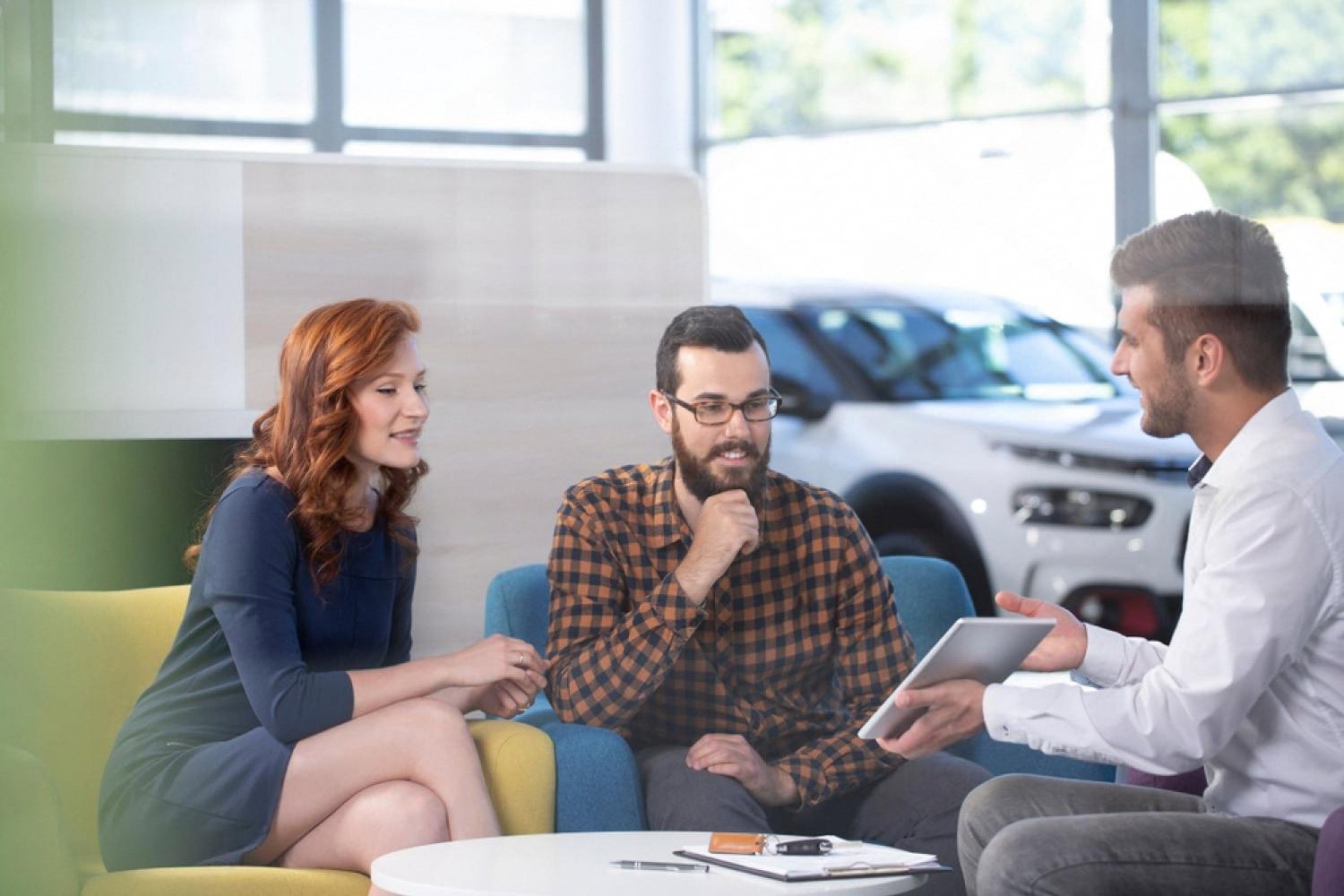 Customers reviewing a rental car agreement with an agent inside a UAE showroom